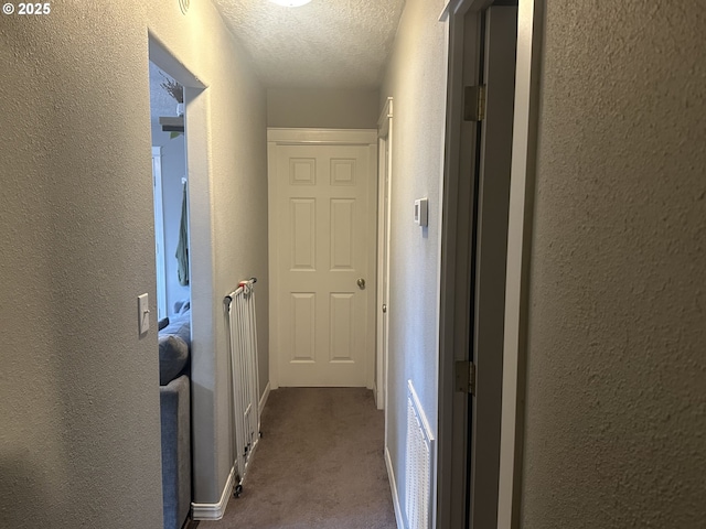 hallway featuring light carpet and a textured ceiling