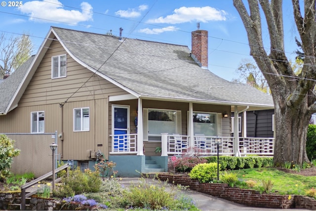 view of front of home with a chimney, roof with shingles, fence, and covered porch