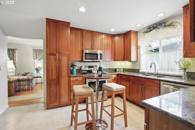 kitchen with recessed lighting, dark stone countertops, stainless steel appliances, and a sink