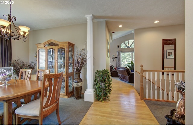 dining area featuring ornate columns, a chandelier, wood finished floors, recessed lighting, and a textured ceiling