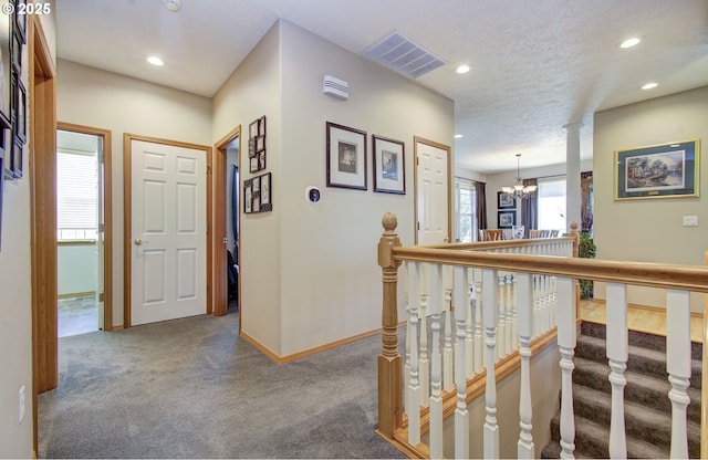 corridor featuring a chandelier, carpet flooring, recessed lighting, baseboards, and a textured ceiling