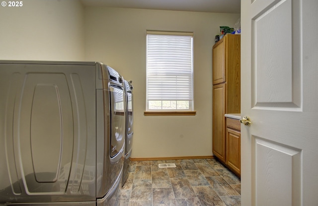 clothes washing area featuring cabinet space, baseboards, independent washer and dryer, and stone finish flooring