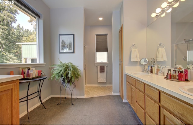 bathroom featuring double vanity, an enclosed shower, baseboards, and recessed lighting