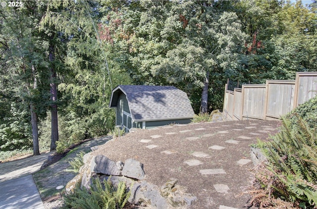 exterior space with a shingled roof, fence, and an outdoor structure