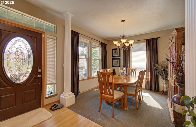 dining room with a chandelier, ornate columns, wood finished floors, and baseboards