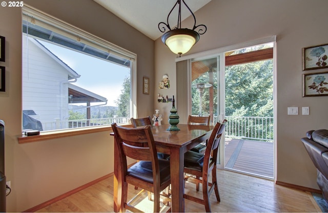 dining room with light wood-style floors, baseboards, and vaulted ceiling