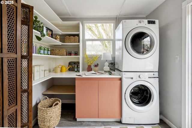 clothes washing area with stacked washer and clothes dryer and laundry area