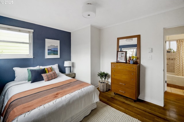 bedroom with ornamental molding, baseboards, and wood finished floors