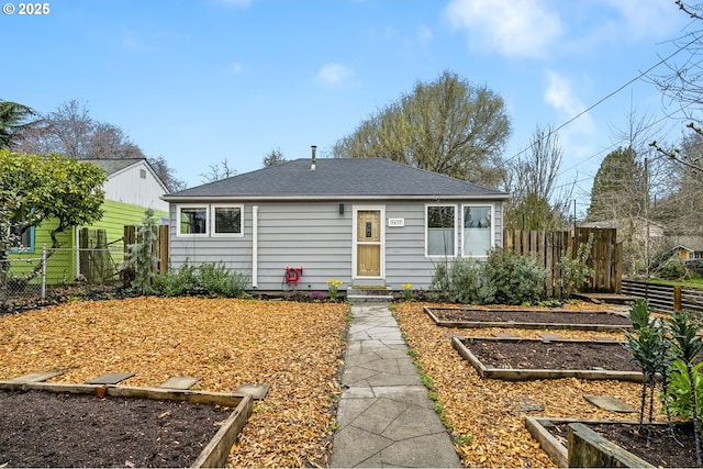 view of front of home featuring a garden, roof with shingles, and fence