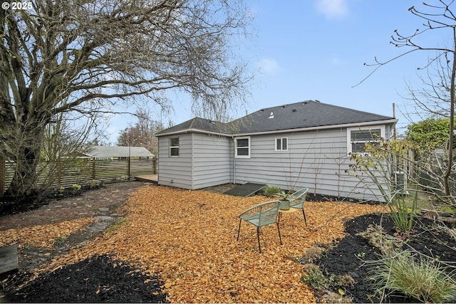 back of house featuring fence and roof with shingles