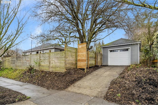 view of home's exterior featuring concrete driveway, an outdoor structure, and fence