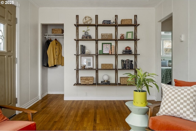 living area featuring crown molding, wood finished floors, and baseboards