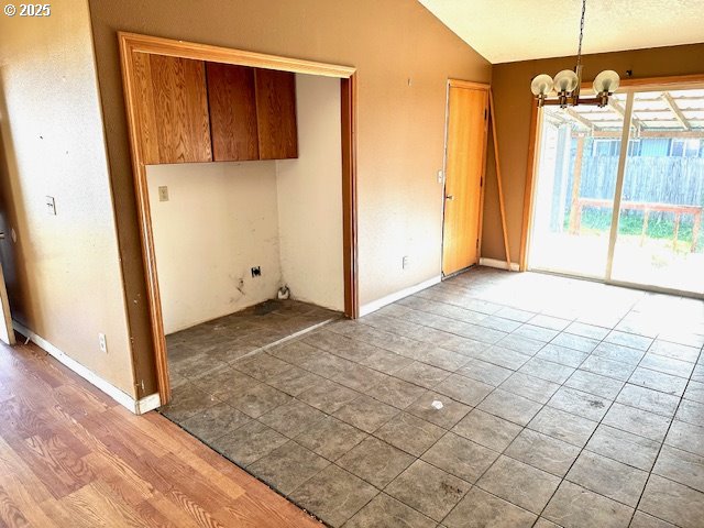 unfurnished dining area featuring vaulted ceiling and a chandelier