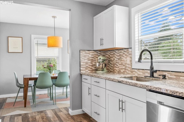 6955 N Concord Ave, Portland, OR 97217 - kitchen with a sink, stainless steel dishwasher, decorative backsplash, baseboards, and white cabinetry