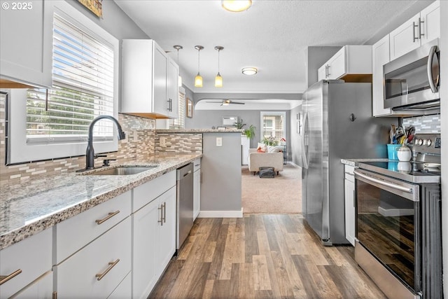 6955 N Concord Ave, Portland, OR 97217 - kitchen with appliances with stainless steel finishes, a sink, wood finished floors, ceiling fan, and white cabinets