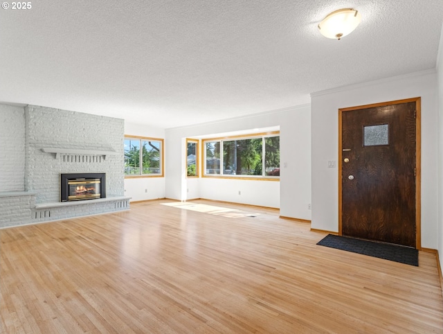 3123 SE 129th Ave, Portland, OR 97236 - unfurnished living room featuring a textured ceiling, wood finished floors, a brick fireplace, and crown molding