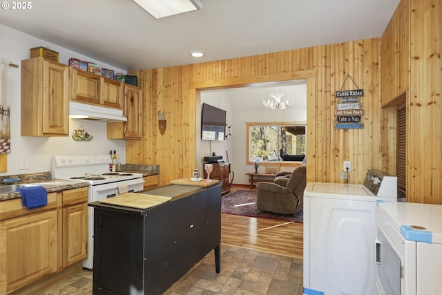 kitchen featuring electric stove, separate washer and dryer, an inviting chandelier, and wood walls