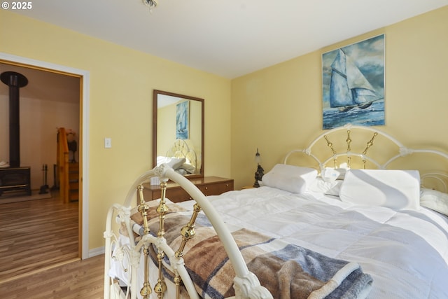 bedroom featuring hardwood / wood-style flooring and a wood stove