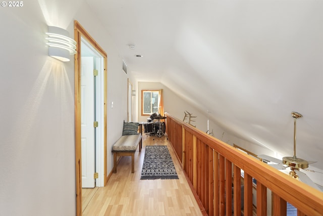 hallway with vaulted ceiling and light hardwood / wood-style flooring