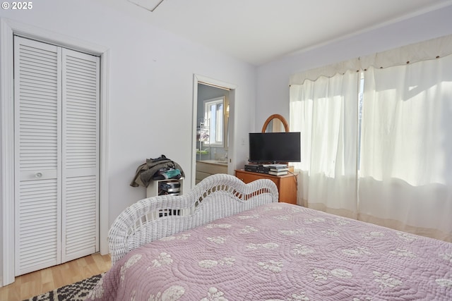 bedroom with hardwood / wood-style floors, ensuite bath, and a closet