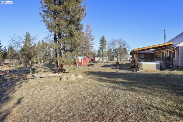 view of yard featuring a hot tub and a storage shed