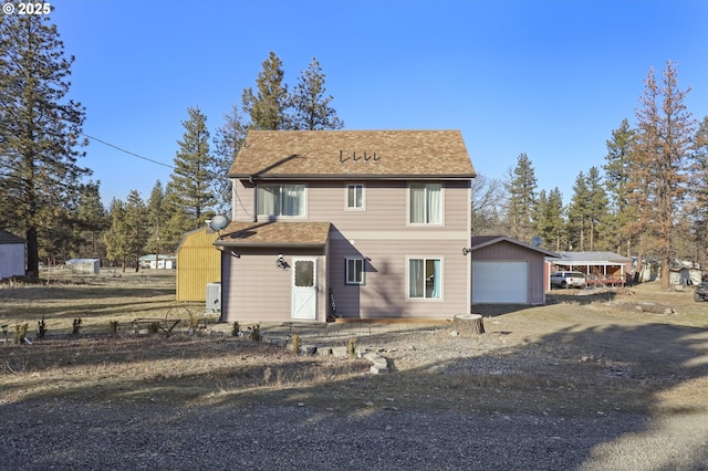 back of house with an outbuilding, a garage, and a carport