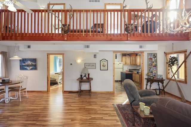 living room with hardwood / wood-style flooring, a towering ceiling, and ceiling fan