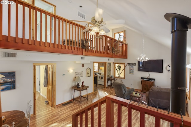 living room with high vaulted ceiling, ceiling fan with notable chandelier, and light hardwood / wood-style floors