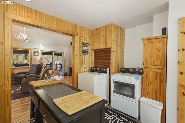 washroom with a chandelier, separate washer and dryer, light hardwood / wood-style floors, and wood walls