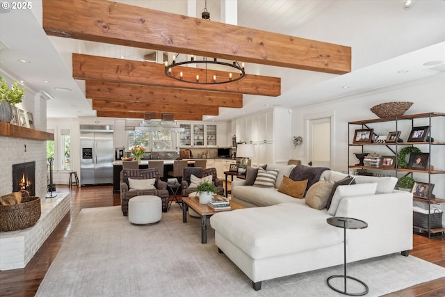 2550 Dellwood Dr, Lake Oswego, OR 97034 - living area with wood finished floors, a chandelier, a brick fireplace, and beam ceiling