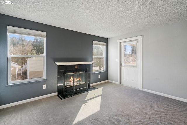 13216 NE Salmon Creek Ave Unit E8, Vancouver, WA 98686 - unfurnished living room featuring a tiled fireplace, carpet floors, a textured ceiling, and baseboards