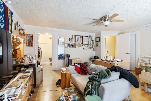 bedroom featuring light wood-style flooring, ornamental molding, a textured ceiling, and a ceiling fan