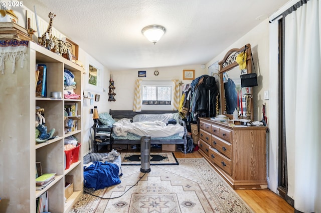 bedroom with light wood-type flooring and a textured ceiling