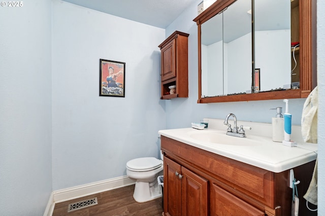 bathroom with baseboards, wood finished floors, toilet, and vanity