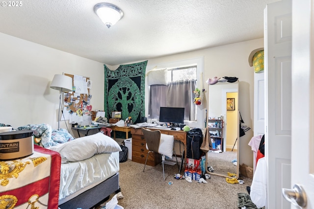 carpeted bedroom with an office area and a textured ceiling