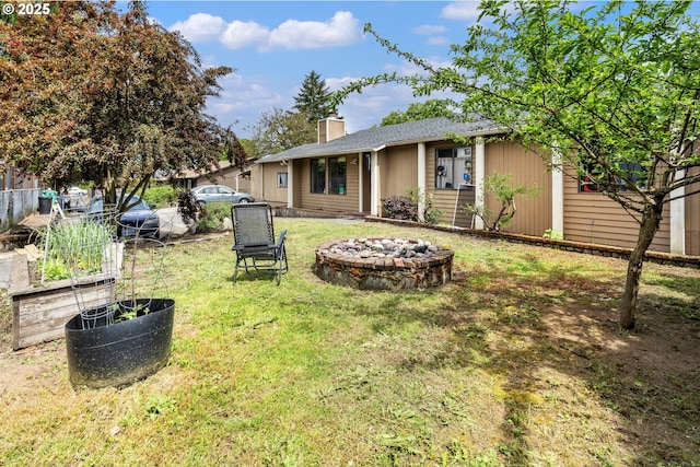 view of grassy yard with an outdoor fire pit