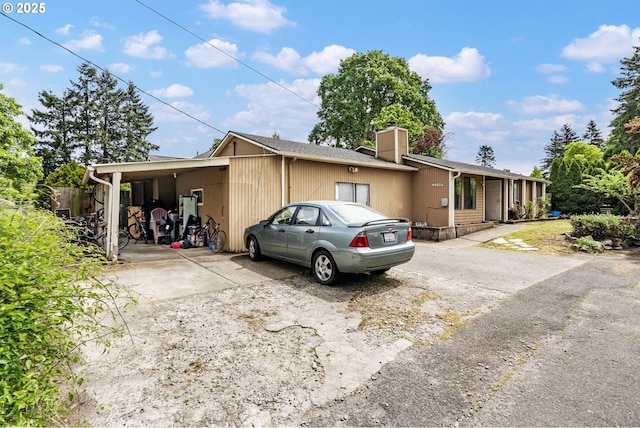 view of front of house featuring a chimney, a carport, and driveway