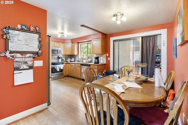 dining room with light wood-style floors, baseboards, and a textured ceiling
