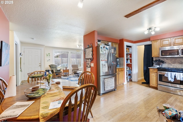 dining area with light wood-type flooring and a textured ceiling
