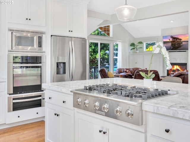 10305 Pine Ridge Dr, Manzanita, OR 97130 - kitchen with stainless steel appliances, open floor plan, vaulted ceiling, a warming drawer, and light stone countertops