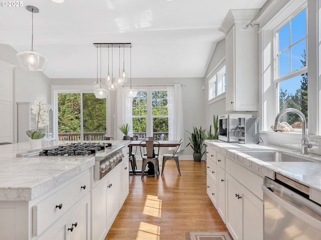 10305 Pine Ridge Dr, Manzanita, OR 97130 - kitchen with appliances with stainless steel finishes, lofted ceiling, light wood finished floors, white cabinetry, and hanging light fixtures