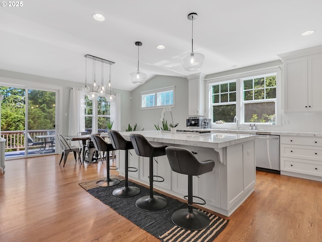 10305 Pine Ridge Dr, Manzanita, OR 97130 - kitchen with dishwasher, a kitchen breakfast bar, a kitchen island, light wood-style flooring, and white cabinetry