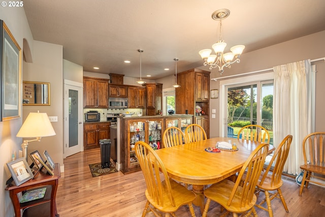 dining room with a toaster, an inviting chandelier, light wood-type flooring, and recessed lighting
