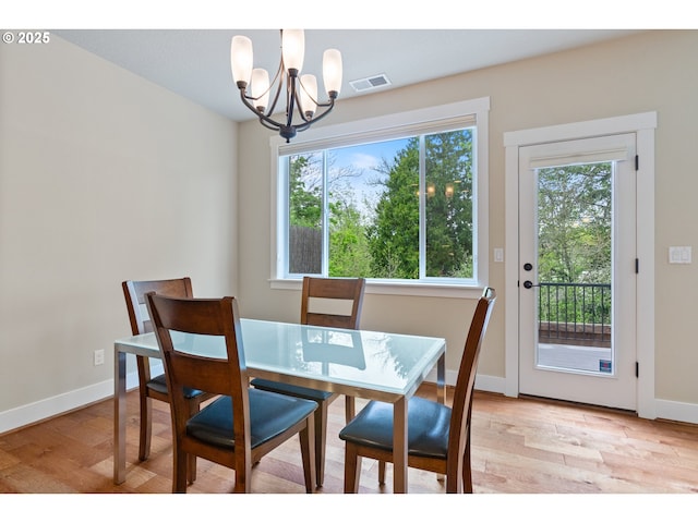 dining area with baseboards, visible vents, light wood-style flooring, and a notable chandelier