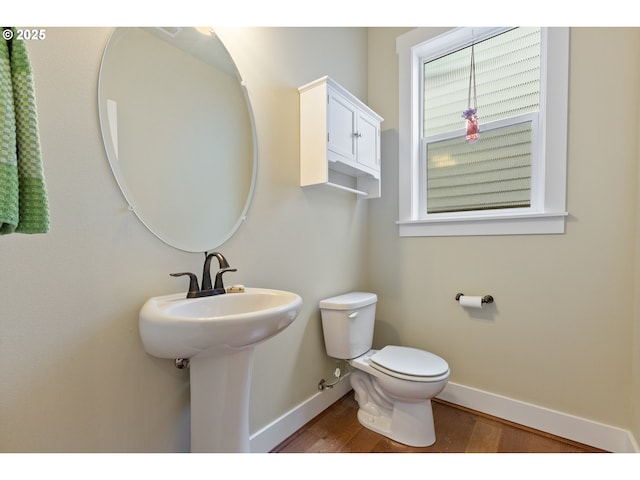 half bathroom featuring baseboards, toilet, and wood finished floors
