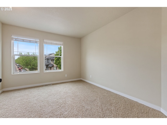 carpeted spare room with baseboards and visible vents