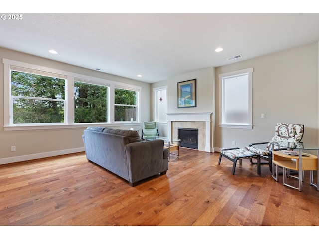 living area featuring light wood-type flooring, a tile fireplace, visible vents, and a healthy amount of sunlight