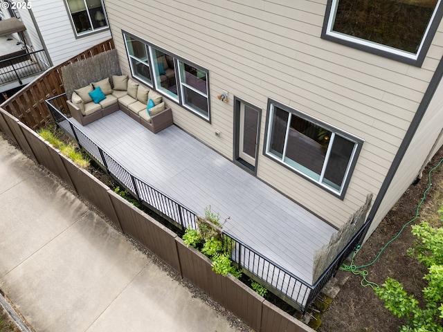 view of side of home featuring fence, a wooden deck, and an outdoor living space