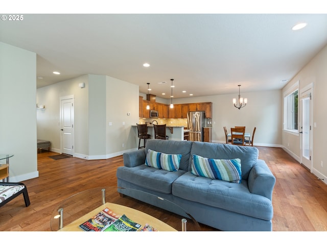 living room featuring an inviting chandelier, recessed lighting, light wood-style floors, and baseboards