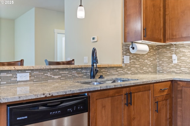 kitchen featuring stainless steel dishwasher, brown cabinetry, a sink, and tasteful backsplash